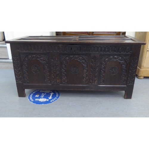 229 - A mid 17thC oak coffer with straight sides and a hinged lid, over a tri-panelled front, raised on bl... 