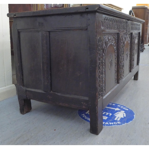 229 - A mid 17thC oak coffer with straight sides and a hinged lid, over a tri-panelled front, raised on bl... 