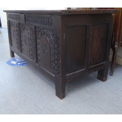 229 - A mid 17thC oak coffer with straight sides and a hinged lid, over a tri-panelled front, raised on bl... 