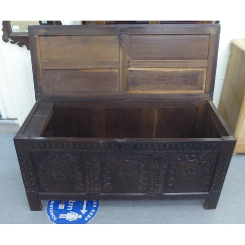 229 - A mid 17thC oak coffer with straight sides and a hinged lid, over a tri-panelled front, raised on bl... 