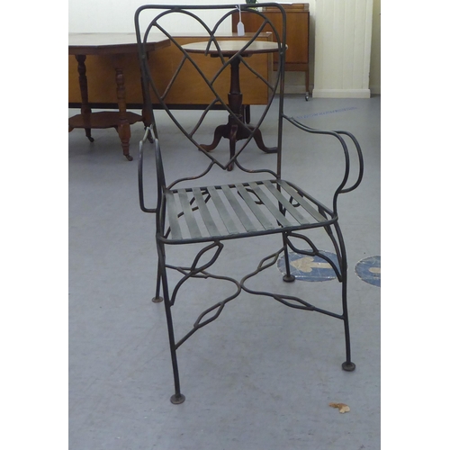 231 - A black painted and part bronzed wrought iron framed terrace chair with a heart shaped back, open ar... 