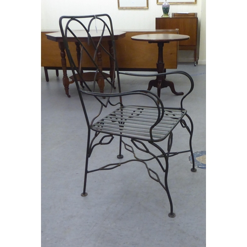 231 - A black painted and part bronzed wrought iron framed terrace chair with a heart shaped back, open ar... 