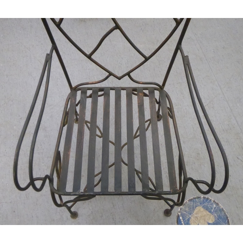 231 - A black painted and part bronzed wrought iron framed terrace chair with a heart shaped back, open ar... 