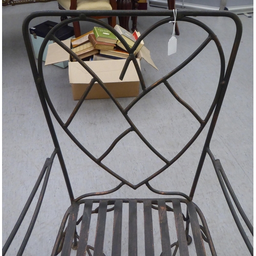 231 - A black painted and part bronzed wrought iron framed terrace chair with a heart shaped back, open ar... 