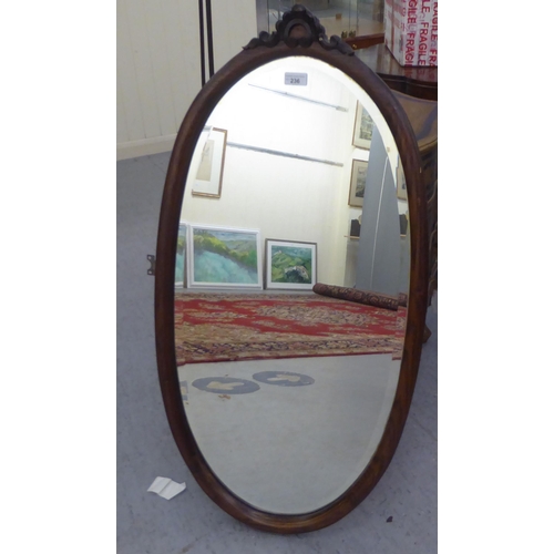 236 - An Edwardian style bevelled oval mirror, set in a carved oak frame  39