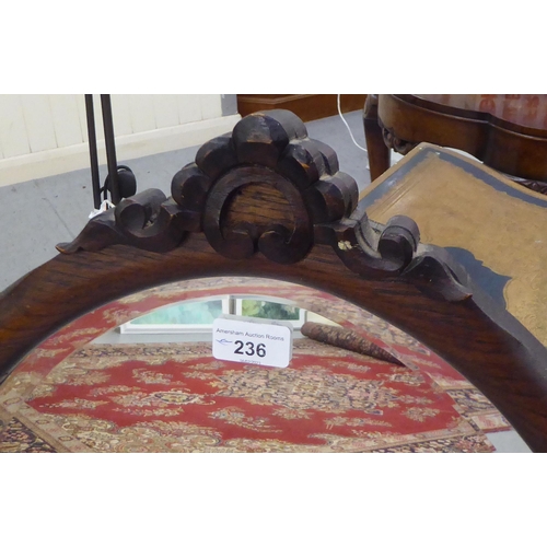 236 - An Edwardian style bevelled oval mirror, set in a carved oak frame  39