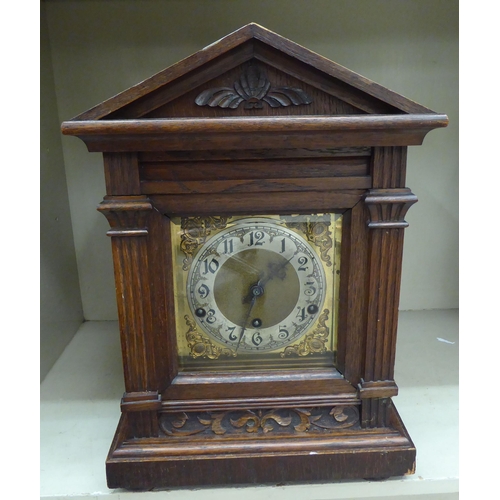 243 - An early 20thC oak cased mantel clock; the chiming movement faced by a silvered and brass Arabic dia... 