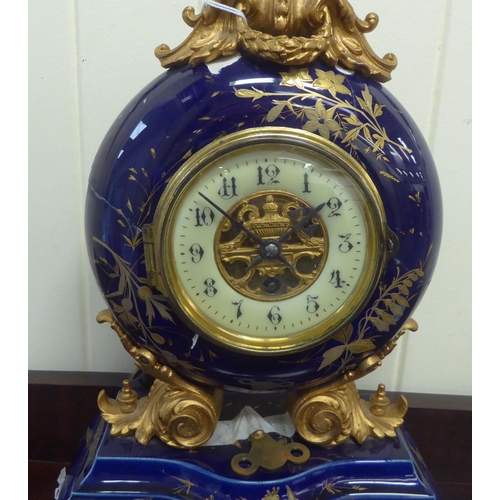 68 - An early/mid 20thC midnight blue china and gilded mantel timepiece with gilt metal mounts; the movem... 