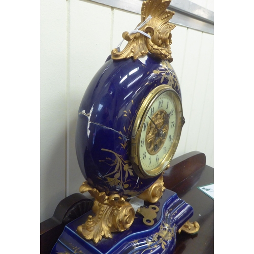 68 - An early/mid 20thC midnight blue china and gilded mantel timepiece with gilt metal mounts; the movem... 