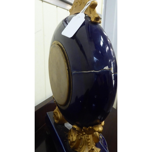 68 - An early/mid 20thC midnight blue china and gilded mantel timepiece with gilt metal mounts; the movem... 