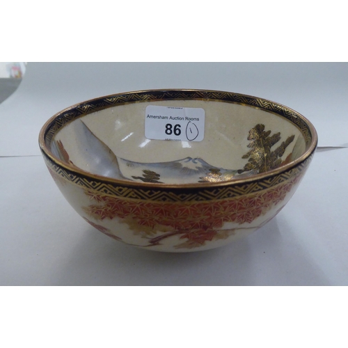 86 - An early/mid 20thC Japanese Satsuma earthenware bowl, traditionally decorated with a landscape and g... 