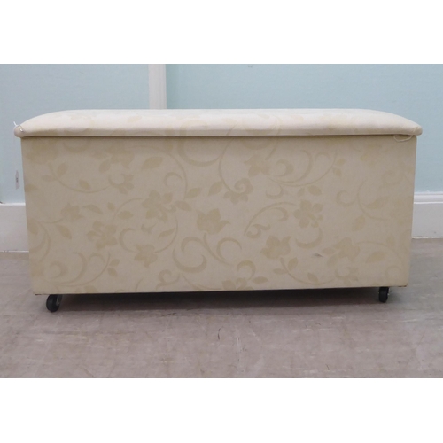 46 - A modern cream coloured fabric upholstered ottoman with straight sides and a cushioned, hinged seat,... 