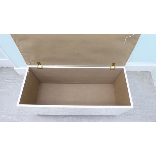 46 - A modern cream coloured fabric upholstered ottoman with straight sides and a cushioned, hinged seat,... 