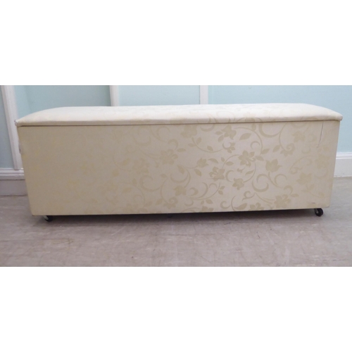 48 - A modern cream coloured fabric upholstered ottoman with straight sides and a cushioned, hinged seat,... 
