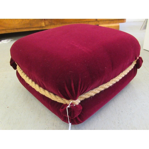 30 - A modern maroon felt effect, fabric upholstered footstool with rope effect trim