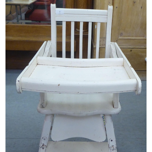 7 - An Edwardian and later painted wooden highchair, the rising tray action top on turned legs, united b... 