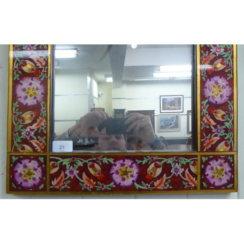 21 - A modern mirror, the plate set in a laminated Asian inspired wooden frame, decorated in bright colou... 