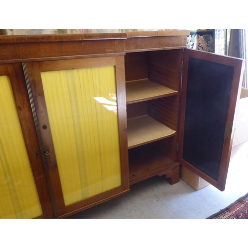 9 - A Regency rosewood and mahogany breakfront sideboard with four glazed doors, raised on bracket feet ... 