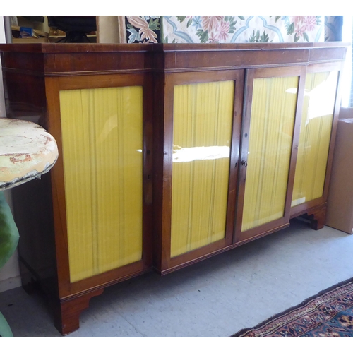 9 - A Regency rosewood and mahogany breakfront sideboard with four glazed doors, raised on bracket feet ... 