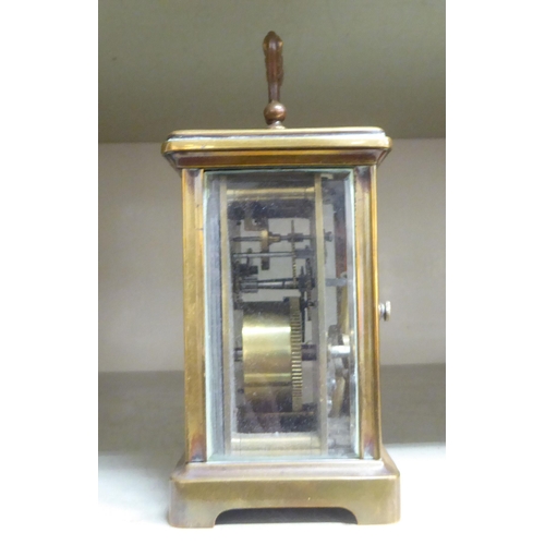 125 - A mid 20thC brass cased carriage timepiece with bevelled glass panels and a folding top handle; the ... 