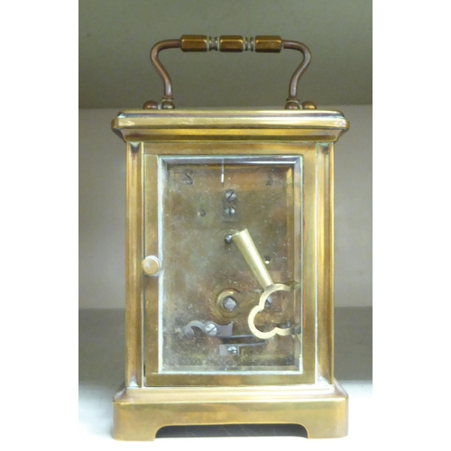 125 - A mid 20thC brass cased carriage timepiece with bevelled glass panels and a folding top handle; the ... 