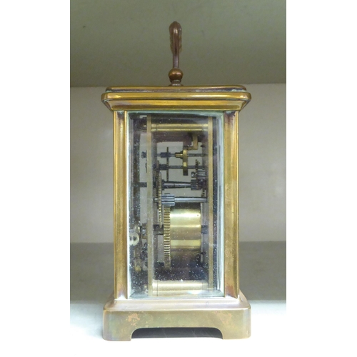 125 - A mid 20thC brass cased carriage timepiece with bevelled glass panels and a folding top handle; the ... 