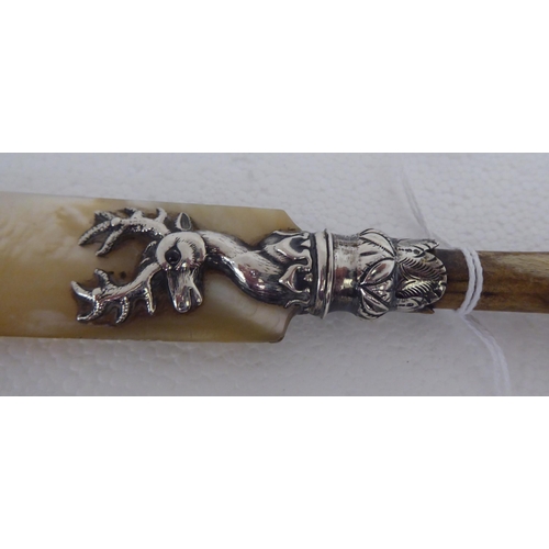 128 - A Victorian paper knife with a mother-of-pearl blade, in a silver stags head ferrule, on a cloven ho... 