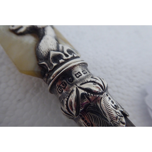 128 - A Victorian paper knife with a mother-of-pearl blade, in a silver stags head ferrule, on a cloven ho... 