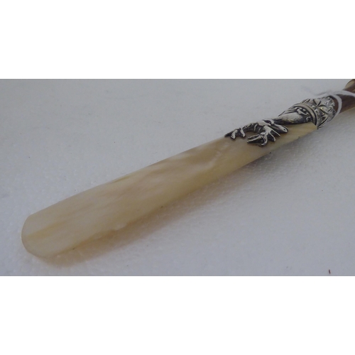 128 - A Victorian paper knife with a mother-of-pearl blade, in a silver stags head ferrule, on a cloven ho... 