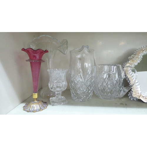 143 - Glassware: to include a late Victorian cranberry coloured trumpet design vase with a cast brass base... 