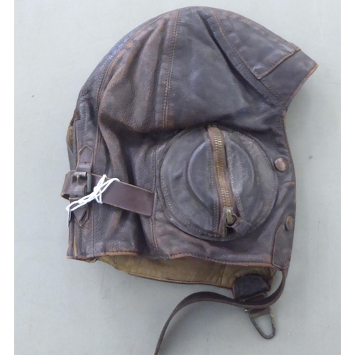 201 - Two brown hide flying helmets; and a pair of googles 