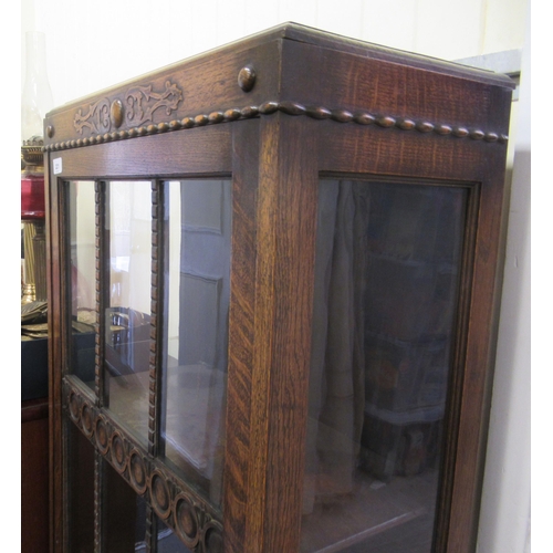 221 - A 1930s oak display cabinet with a single astragal glazed door, raised on bulbous turned legs and bl... 