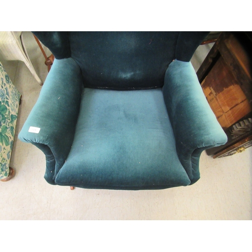 225 - An Edwardian wingback chair, upholstered in blue fabric, raised on square, tapered legs and casters&... 