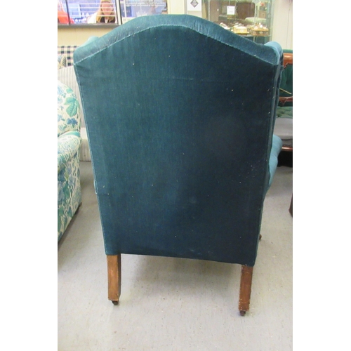 225 - An Edwardian wingback chair, upholstered in blue fabric, raised on square, tapered legs and casters&... 