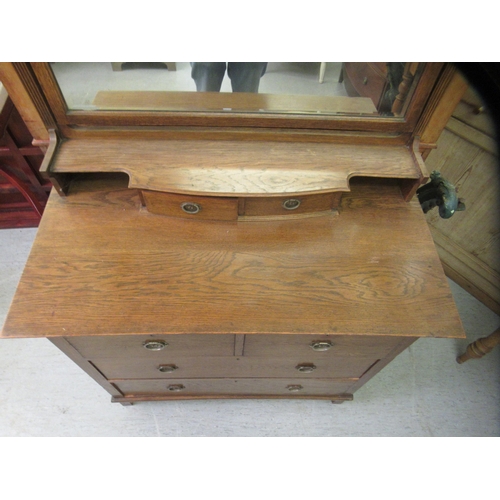 227 - A 1930s Arts & Crafts inspired oak dressing table, the bevelled mirror pivoting on square horns,... 