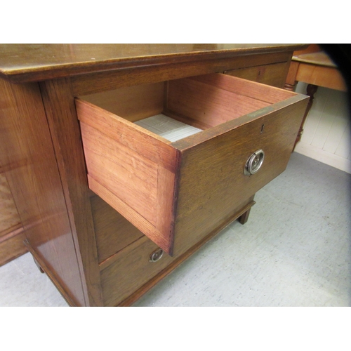 227 - A 1930s Arts & Crafts inspired oak dressing table, the bevelled mirror pivoting on square horns,... 