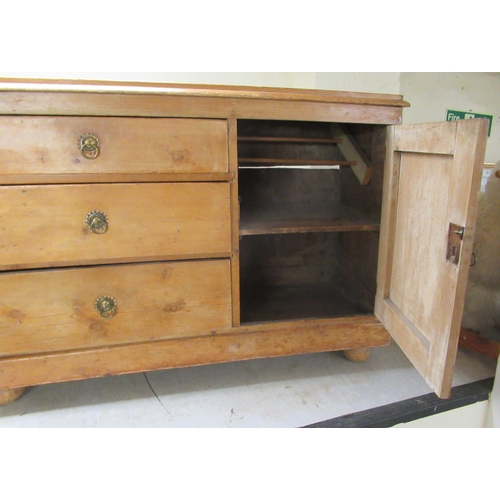 250 - An early 20thC waxed pine sideboard with a bank of three graduated drawers and an adjacent panelled ... 