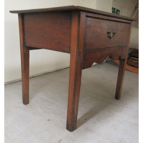 255 - An early 19thC oak lowboy with a single deep drawer and brass bail handle, over a fretworked apron, ... 