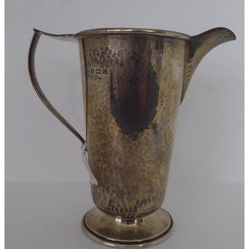 279 - A spot-hammered silver jug of tapered form, on a splayed pedestal foot  Birmingham 1931