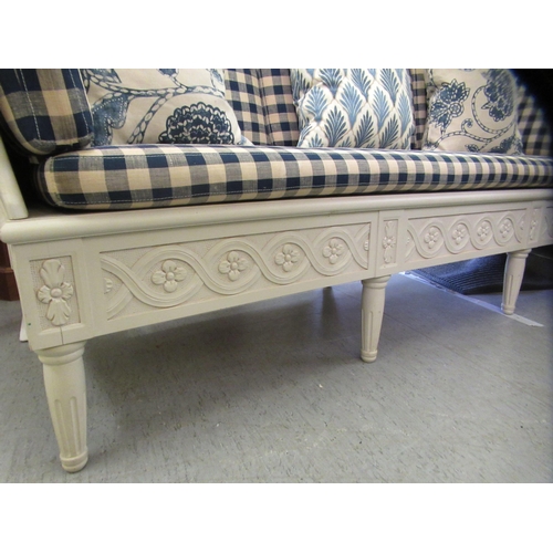 282 - An Ikea French style part carved cream coloured wooden framed settee with a level back and enclosed ... 