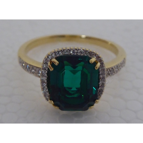 285 - A gold coloured metal claw set, simulated emerald and diamond ring 