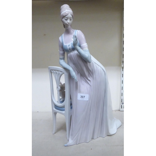 307 - A Lladro porcelain figure, a lady wearing a long gown, standing bedside a chair  model no.1276  19