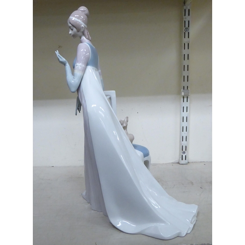 307 - A Lladro porcelain figure, a lady wearing a long gown, standing bedside a chair  model no.1276  19