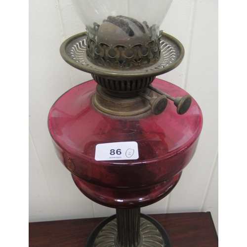 86 - A late Victorian oil lamp with a cranberry coloured glass reservoir  16