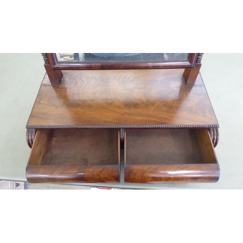 212 - A William IV mahogany toilet mirror, the rectangular plate set on reeded horns, pivoting on a two dr... 