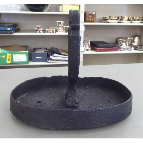 214 - A 19thC black painted cast iron boot scraper, on an oval tray base 