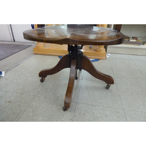 215 - An early 20thC oak framed round back desk chair with open arms and a solid seat, rotating and raised... 