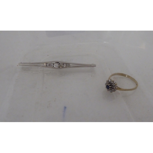 258 - A white metal bar brooch, claw set with seven graduated diamonds; and a 15ct gold claw set sapphire ... 