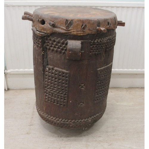 62 - An early 20thC North African tribal drum of barrel design with chip carved ornament and a stretched ... 