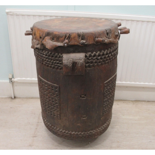 62 - An early 20thC North African tribal drum of barrel design with chip carved ornament and a stretched ... 